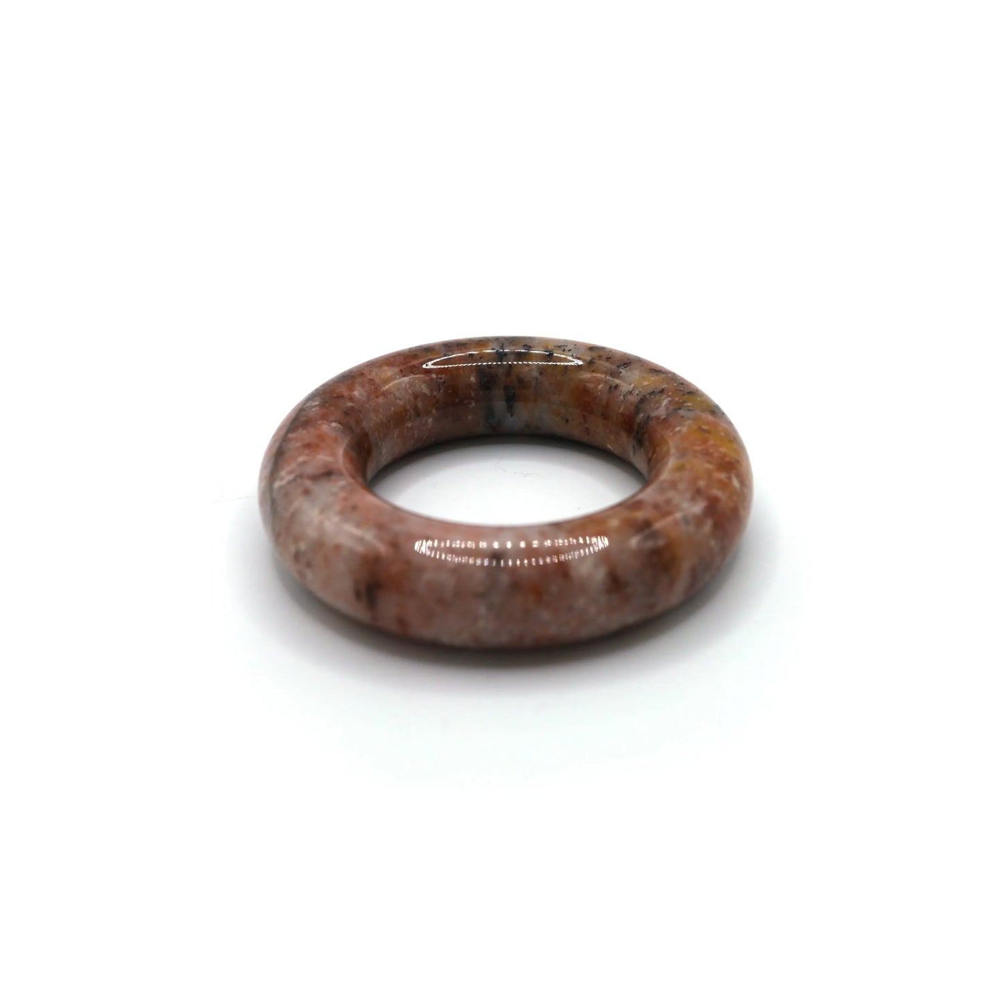 Jade bracelet resting on soft fabric, blending gentle pink tones with natural splashes of warm and dark mineral hues – Miruzi