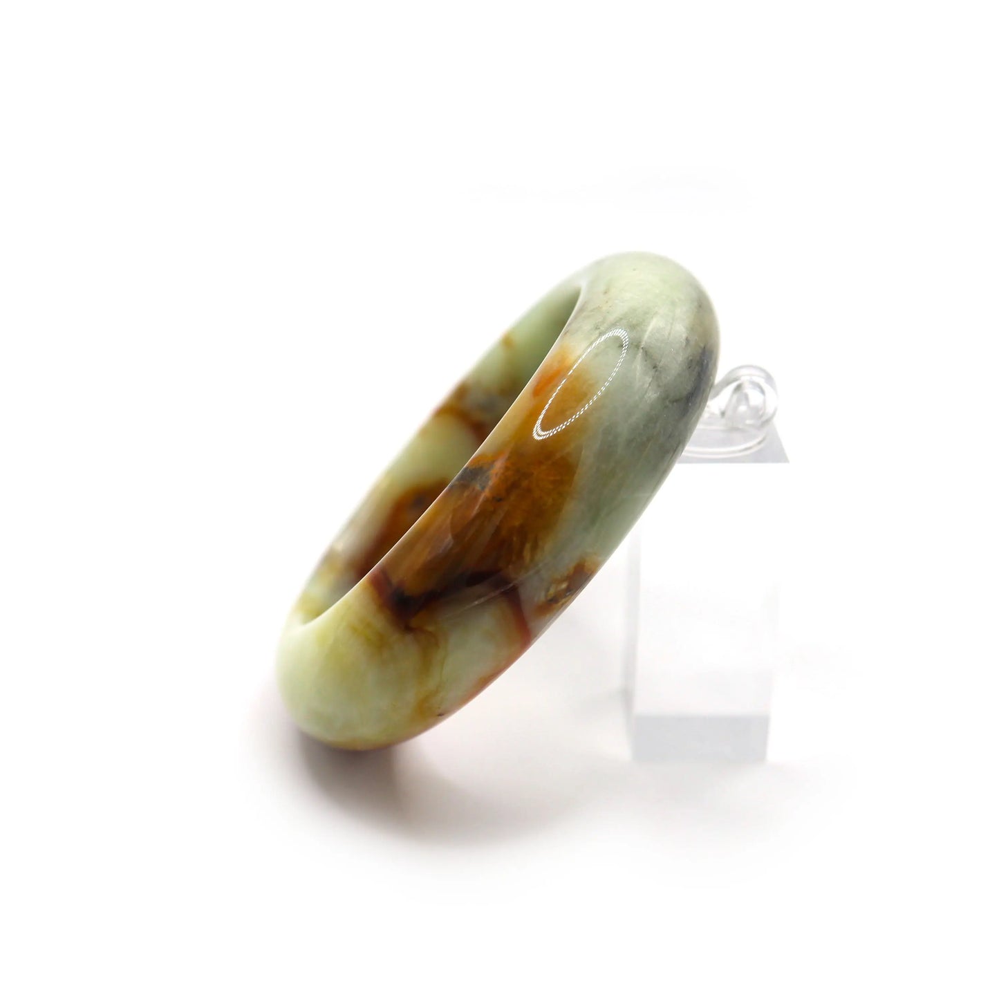 Jade bracelet with red vein detail displayed beside dried branches and dark fabric Miruzi