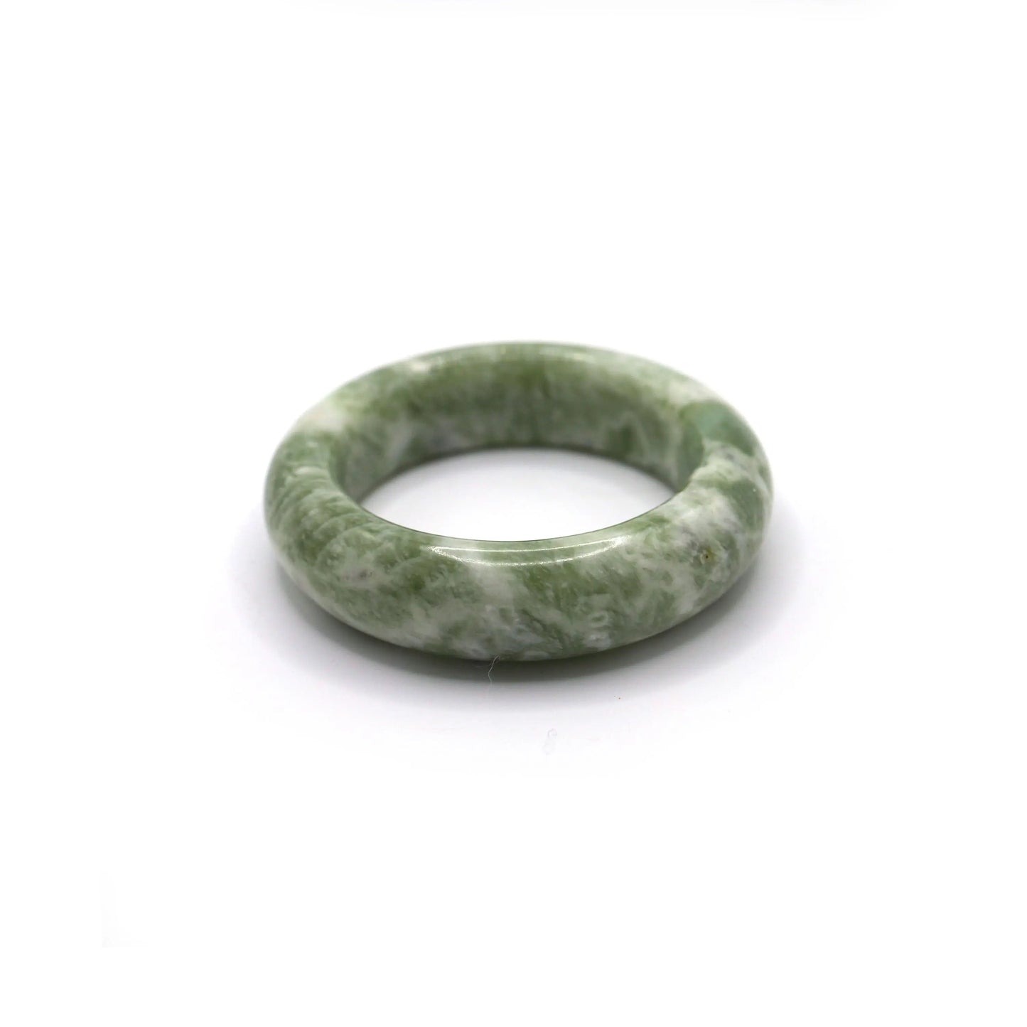 Pale green jade bangle with milky white veining resting on neutral fabric - Miruzi