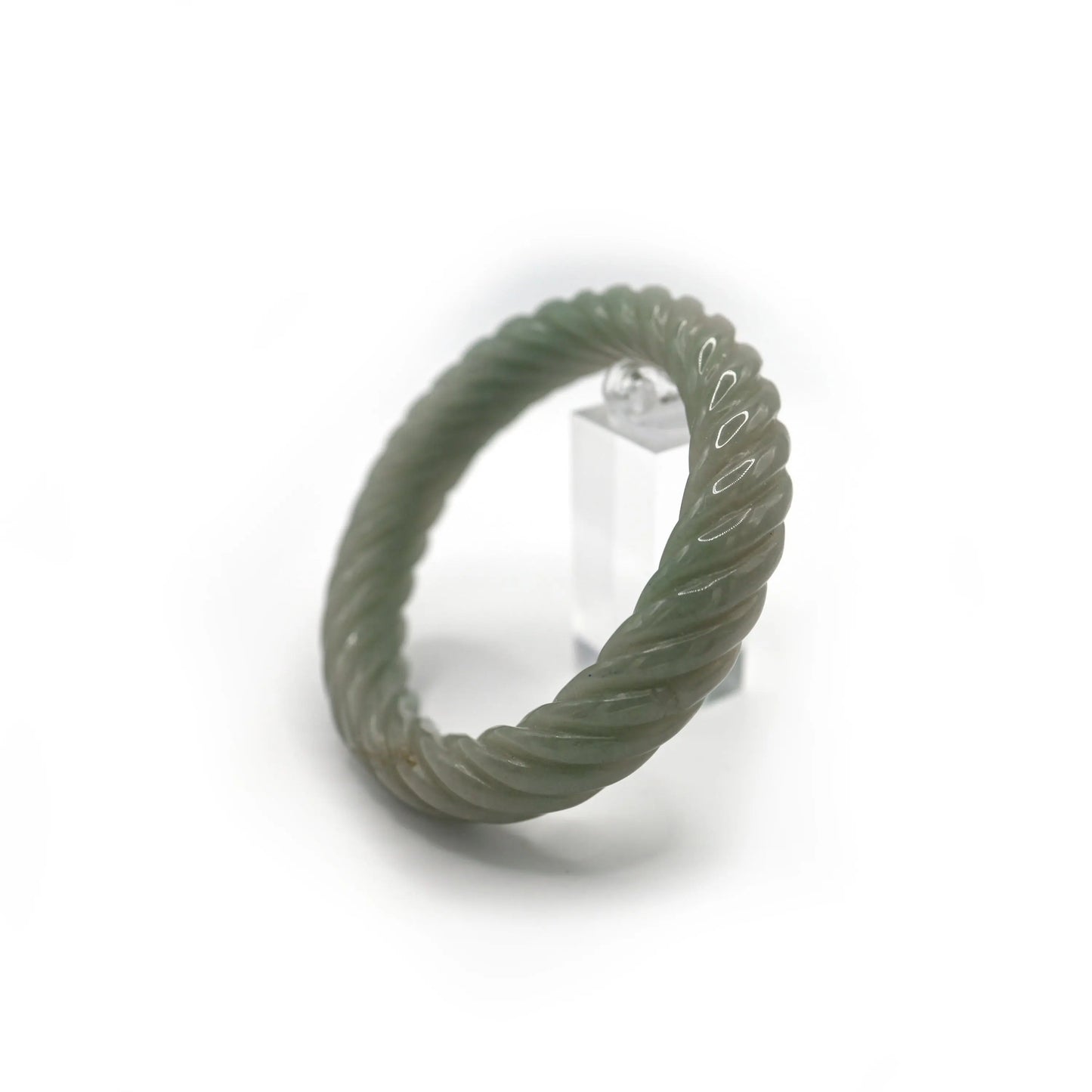 Hand-carved twisted jade bangle with fluid spiral form and ancient coin carvings, offering motion, luck, and elegant tradition – Miruzi