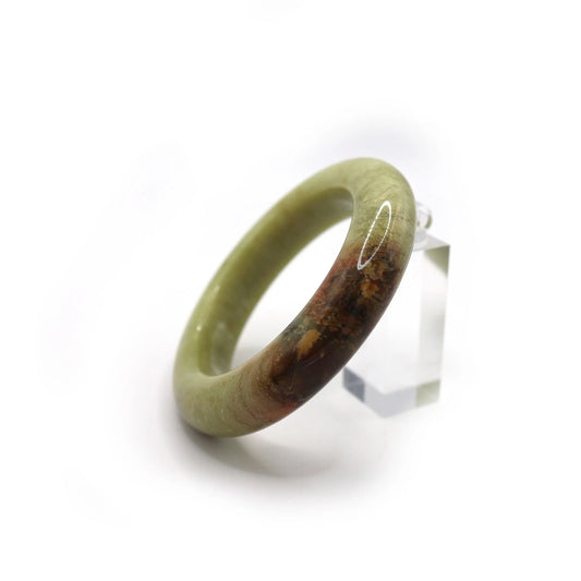 Close-up of jade bracelet showing red-brown mineral vein in soft green stone Miruzi