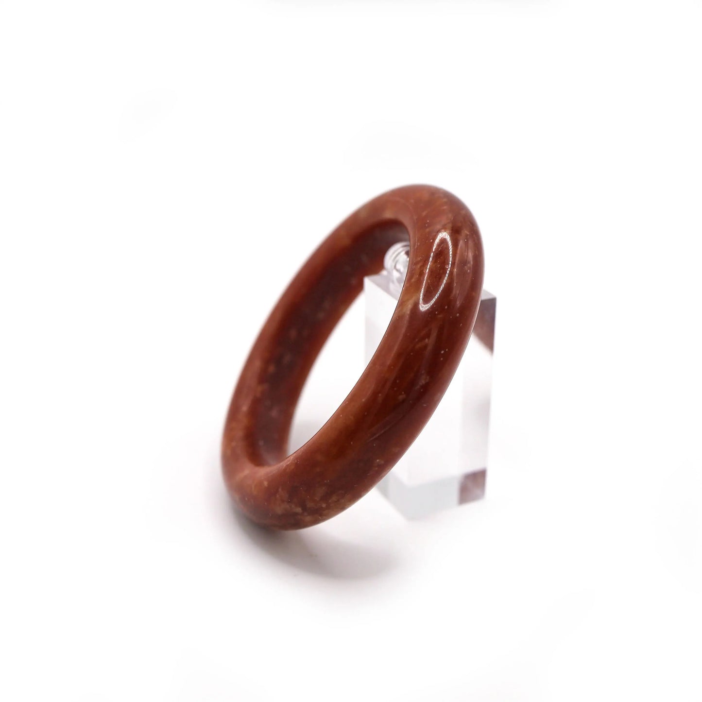 Handmade red jade bracelet on a wooden surface with soft silk accents