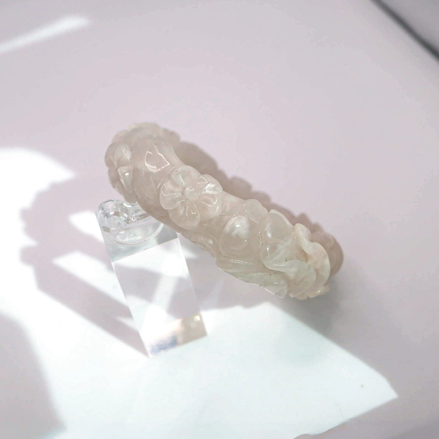 Delicate jade bangle featuring symbolic flowers carved in translucent blush and ivory jade