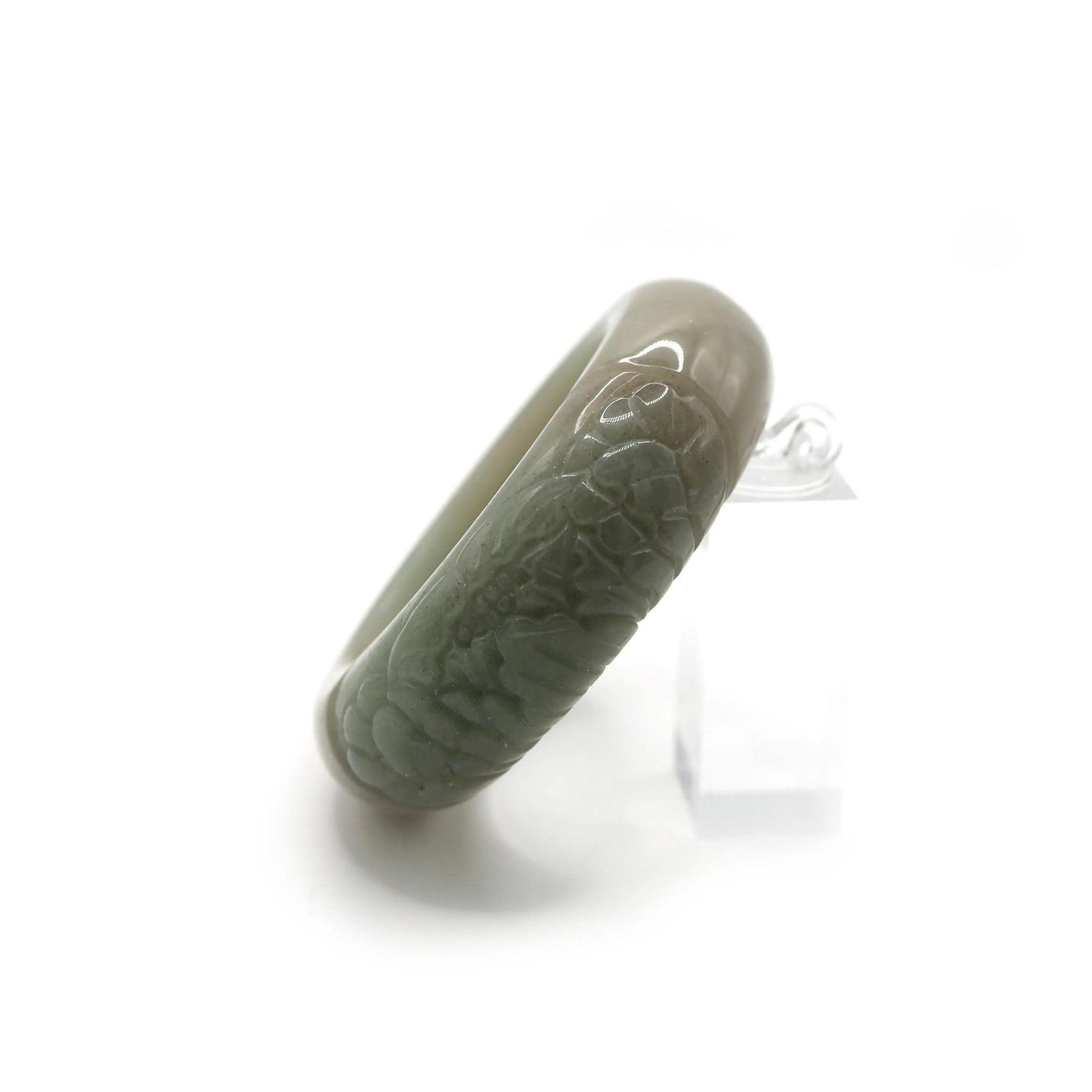 Soft green jade bracelet with subtle surface polish and a single botanical carving, symbolizing nature’s calm strength – Miruzi
