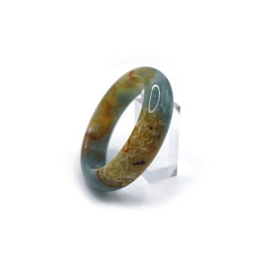 Close-up of handcrafted blue jade bracelet showing flowing mineral veins across a tranquil blue base, reminiscent of sea currents – Miruzi