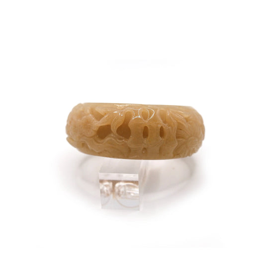 Close-up of wide yellow jade bracelet with detailed carvings of plum blossom, orchid, bamboo, and chrysanthemum on glowing quartzite – Miruzi