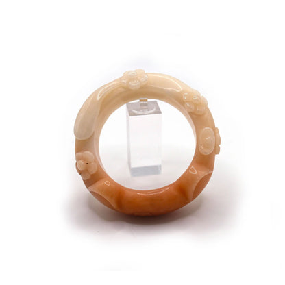 Artisan-crafted cat-themed jade bangle in warm coral tones, showcasing raised floral motifs and a natural surface mark near the right ear – Miruzi