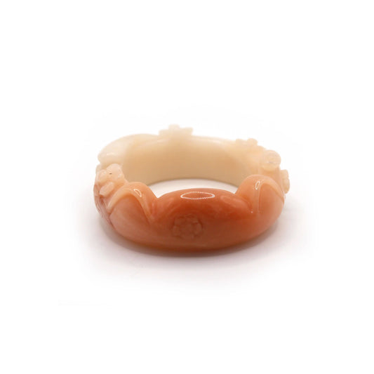 Hand-carved pink-orange jade bracelet with cat ears, a curling tail, and raised blossoms, featuring a small natural mark near one ear – Miruzi