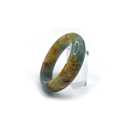 Full jade bracelet on white surface, featuring a polished ocean-blue tone with embedded white and golden veins throughout – Miruzi