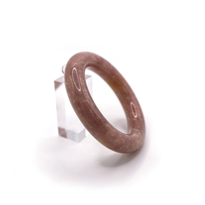 Slim-profile jade bracelet resting on blush silk, showcasing a pale violet tone with scattered natural white starry inclusions – Miruzi