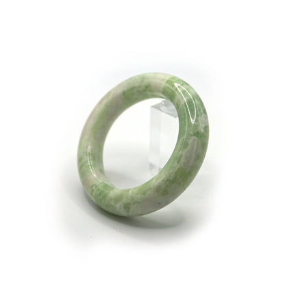 Green jade bangle resting in a soft pouch for elegant presentation and storage Miruzi