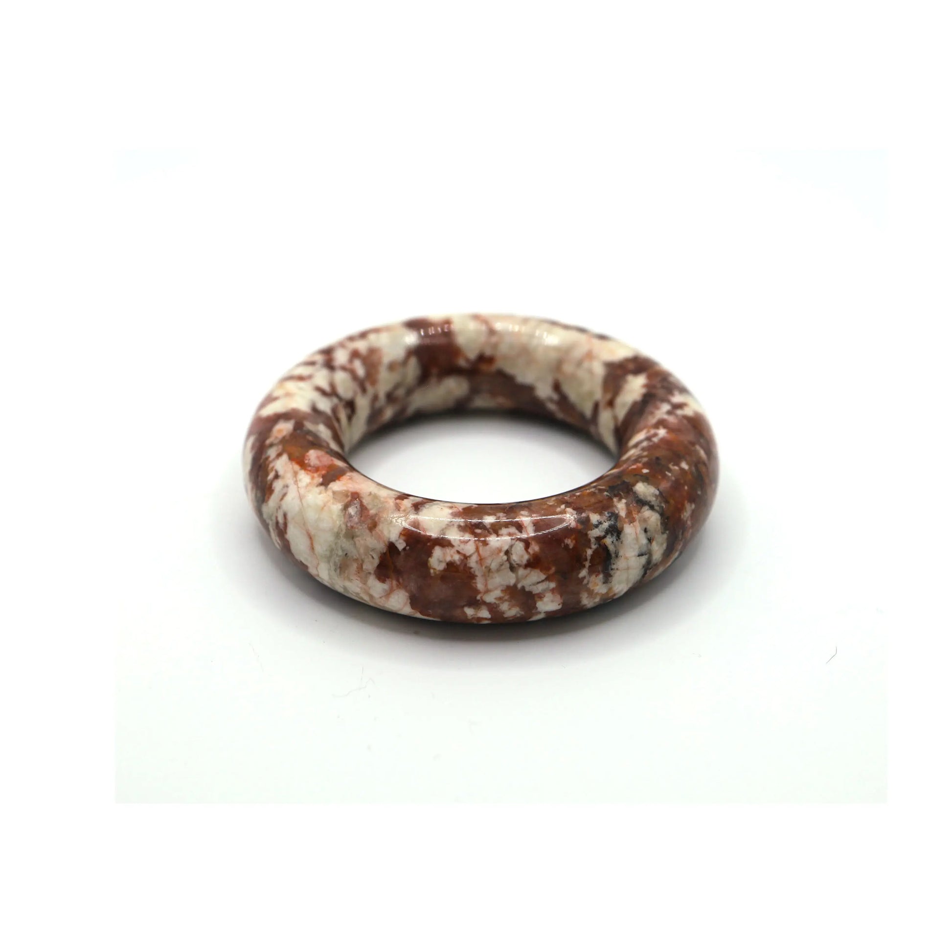Smooth crimson jade bracelet with white popcorn-like inclusions, resting on ivory fabric to emphasize its vibrant energy – Miruzi