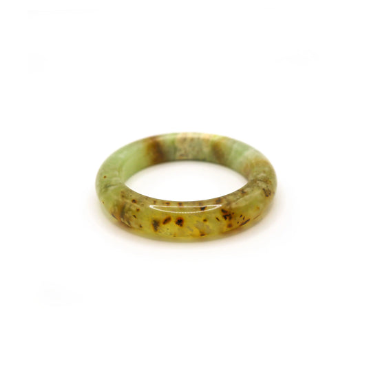 Translucent honey jade bangle with cloudy inclusions placed on neutral linen - miruzi