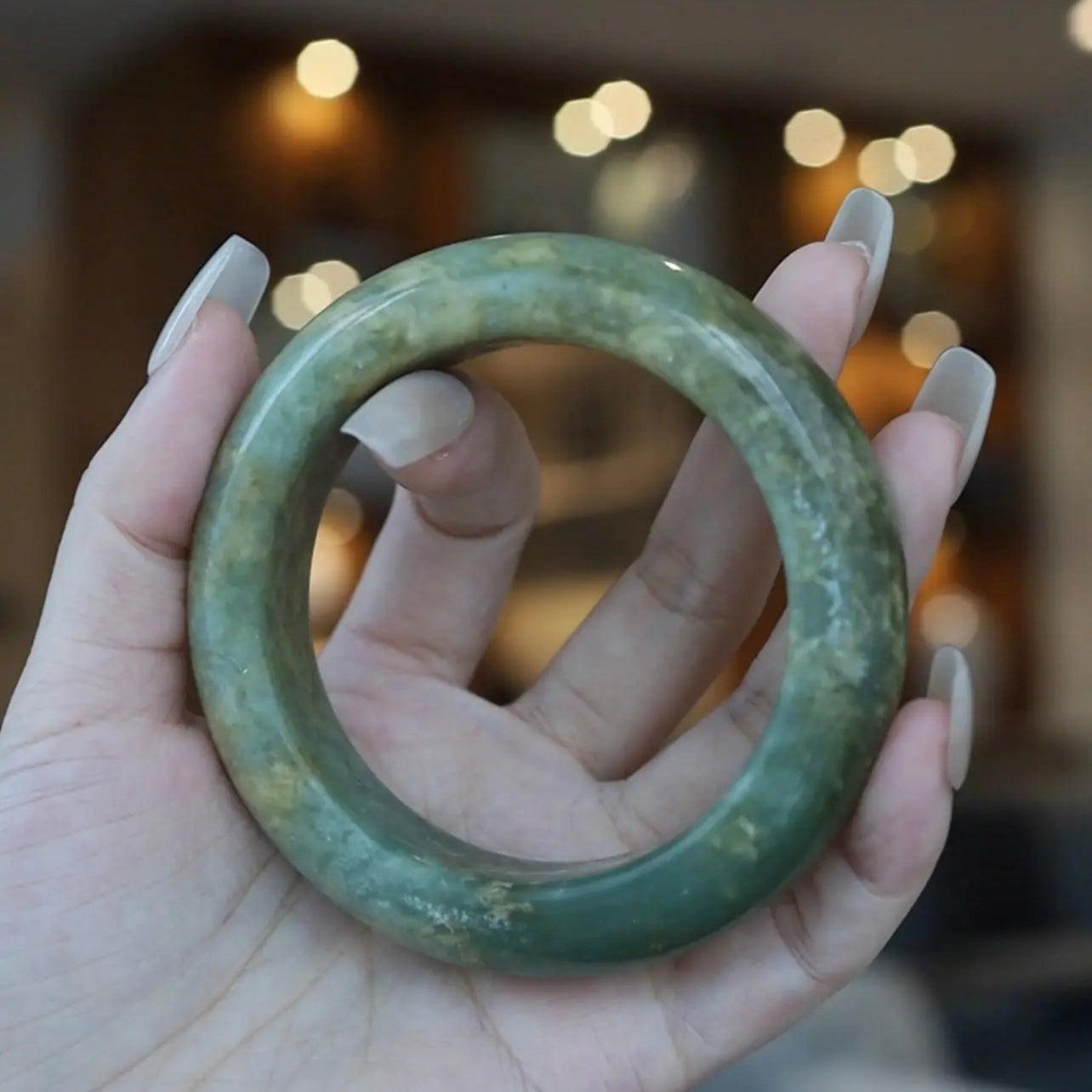Hand-polished serpentine jade bangle in warm golden-green tones with organic gradients, crafted in a traditional full-circle silhouette for small wrists – Miruzi

