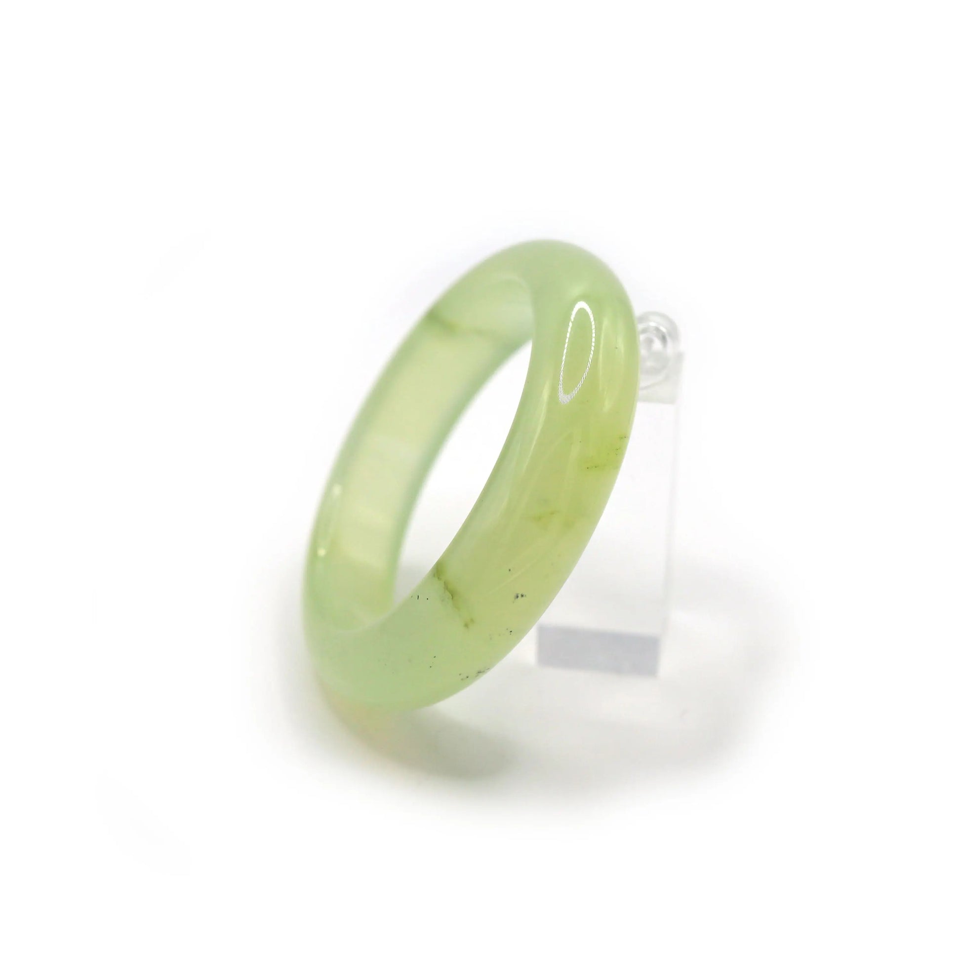 Polished pale green jade bracelet displayed on white linen, reflecting light like chilled glass and evoking a sense of calm clarity – Miruzi