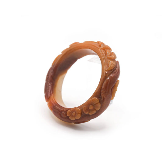 Hand-carved jade bangle featuring a sculpted lotus surrounded by intricate floral details, glowing with fiery translucence – Miruzi