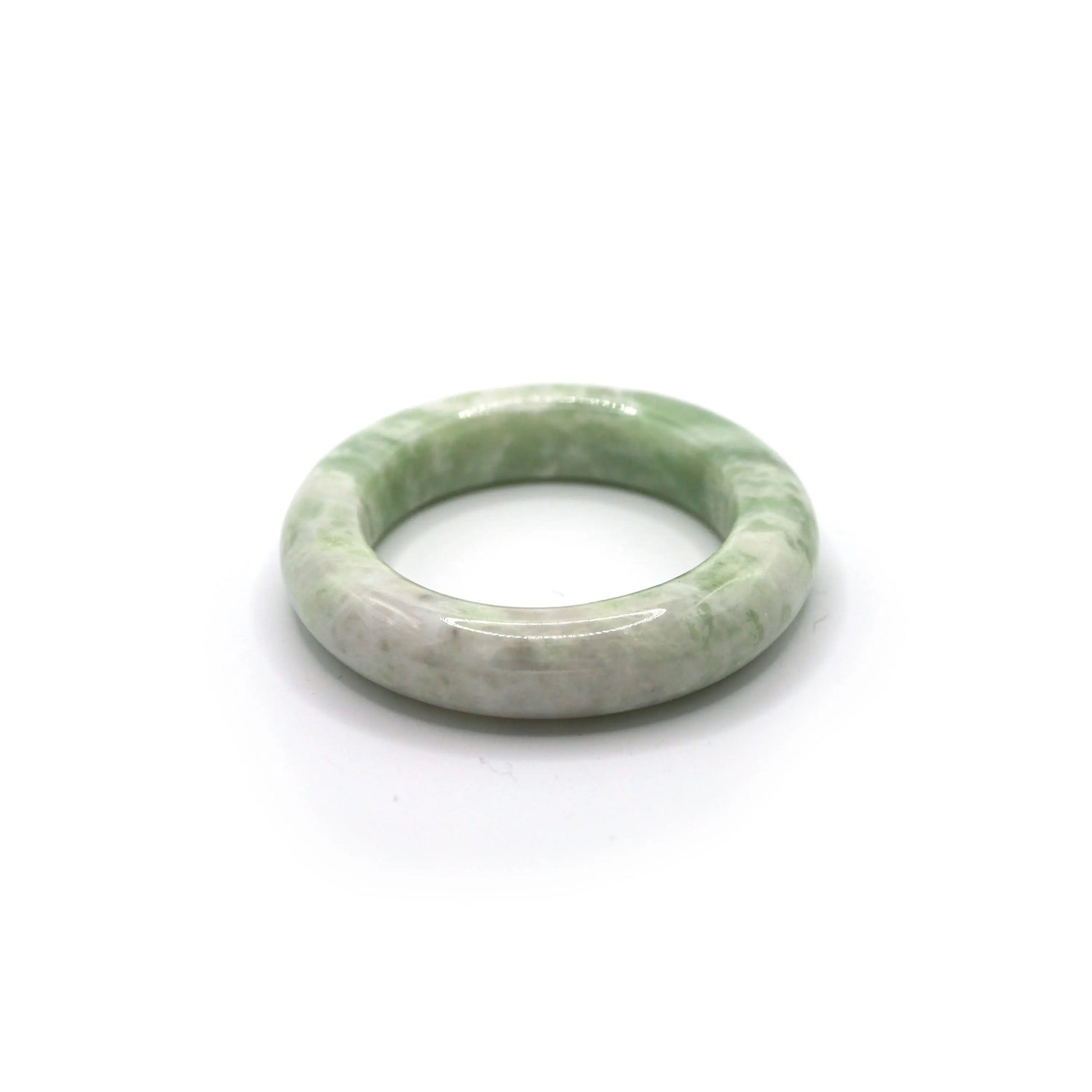 Jade bangle styled beside fog-colored linen and soft pistachio fabric Miruzi