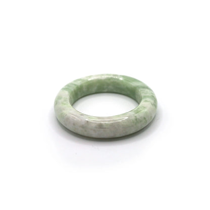 Jade bangle styled beside fog-colored linen and soft pistachio fabric Miruzi