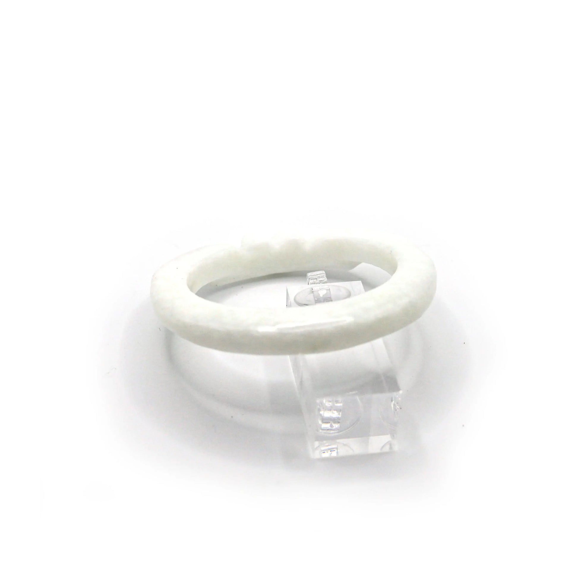 White jade bangle with clean lines and gentle engraving, resting on a blush-toned fabric to enhance its luminous softness – Miruzi