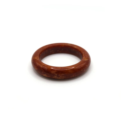Woman wearing red jade bangle styled with neutral-toned linen outfit