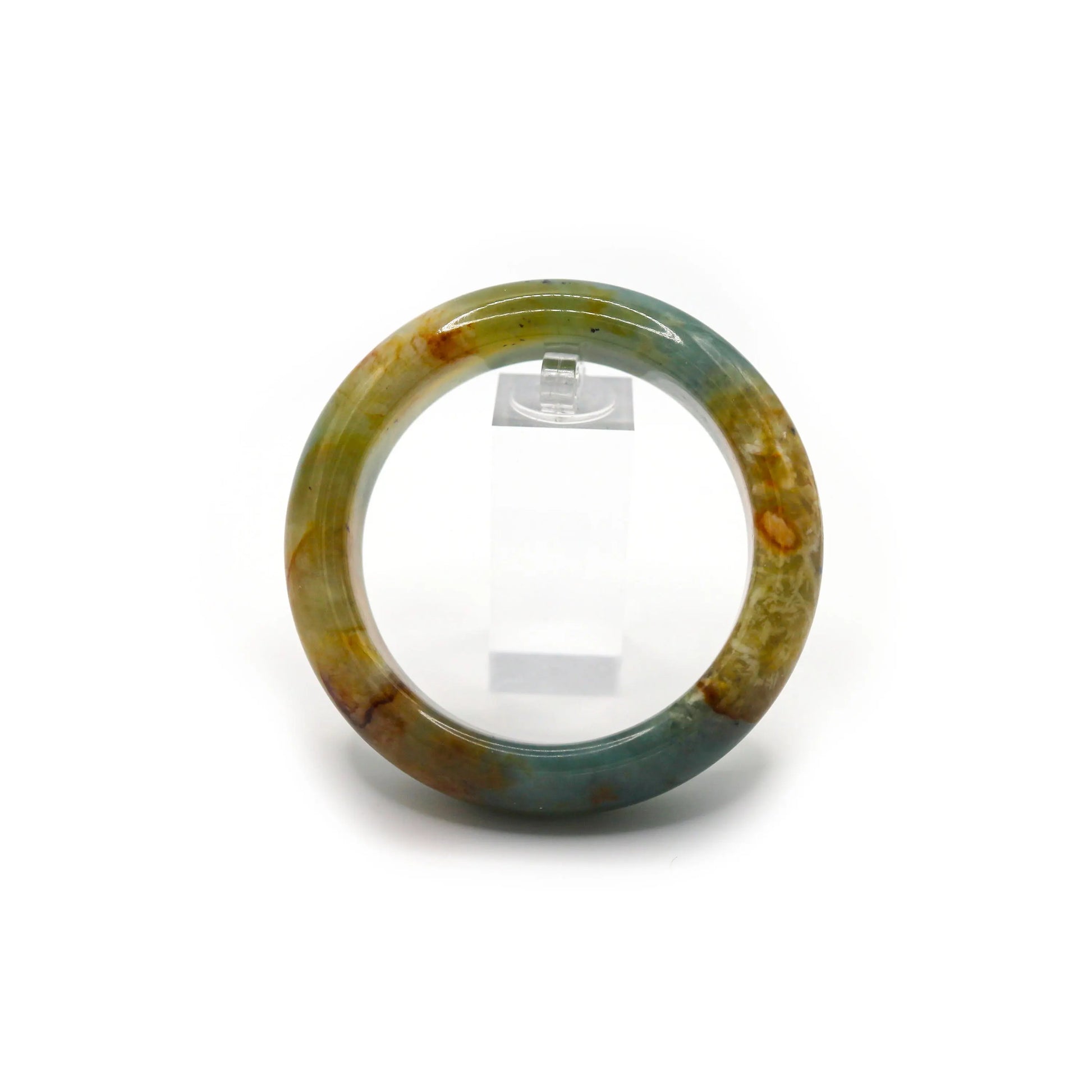 Hand-carved jade bangle photographed with navy and ivory textiles, echoing the sea-like depth of the stone’s color – Miruzi