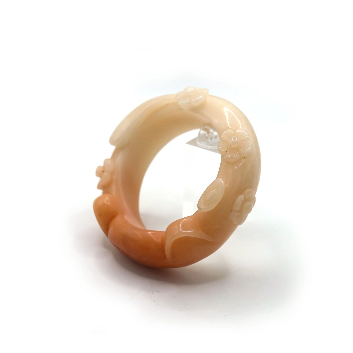 Sculptural jade bracelet with dimensional cat ears, blossoms, and tail, glowing in coral hues with a slight carving mark between details – Miruzi

