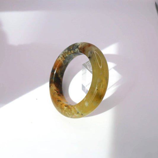 Golden jade bracelet featuring painterly veining in black, beige, and brown with a luminous polished surface

