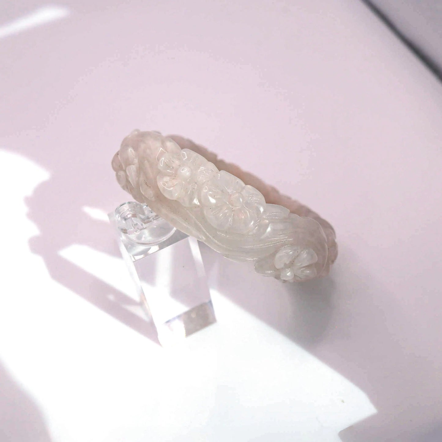 Light pink jade bracelet with artisan floral engraving in peony and plum blossom motif


