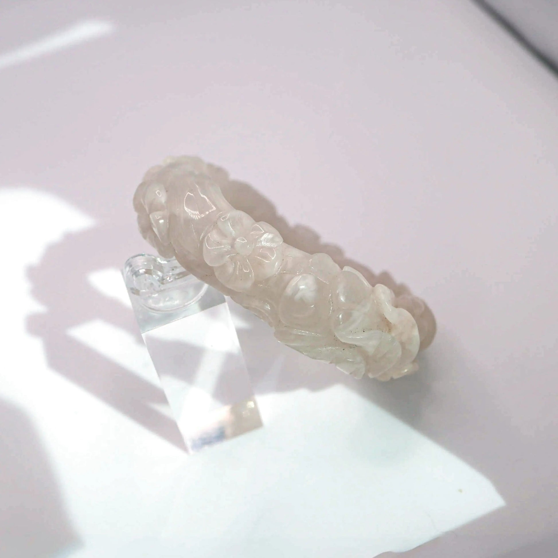 Delicate jade bangle featuring symbolic flowers carved in translucent blush and ivory jade

