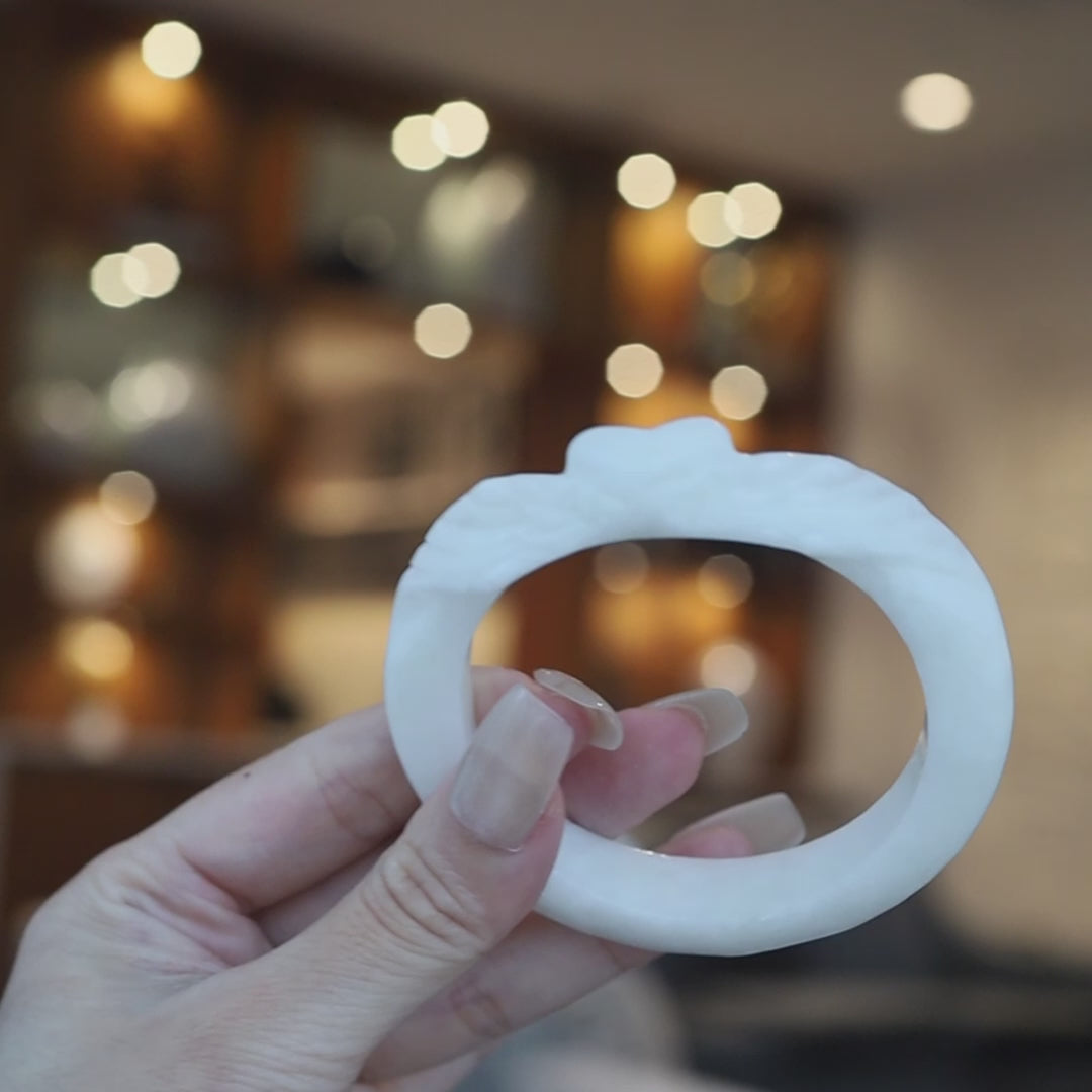 Slim white Mongolian jade bracelet featuring delicate heart and feather carvings, glowing with soft translucency and minimalist elegance – Miruzi