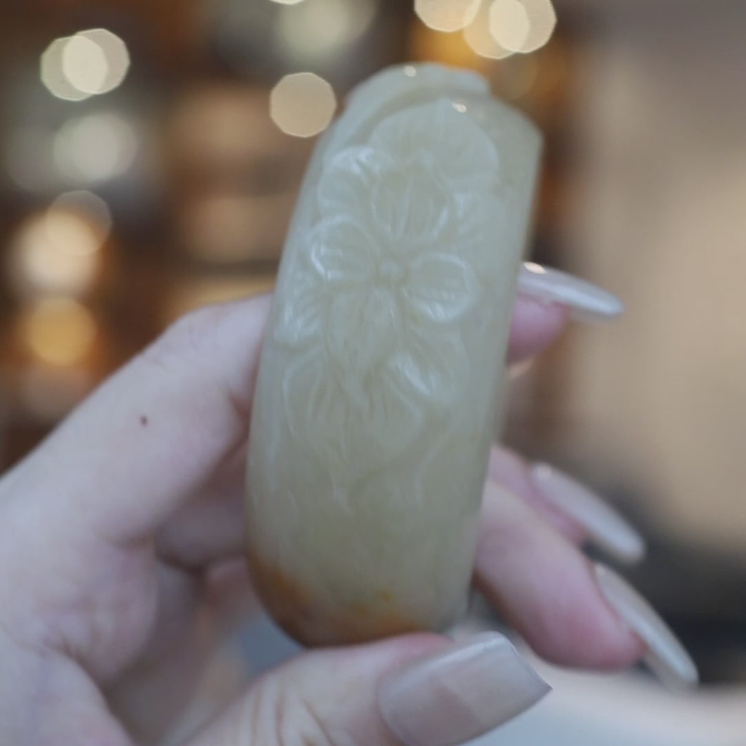 Hand-carved Mongolian yellow jade bracelet featuring plum, orchid, bamboo, and chrysanthemum motifs in high relief, with a soft golden tone and natural orange inclusion – Miruzi