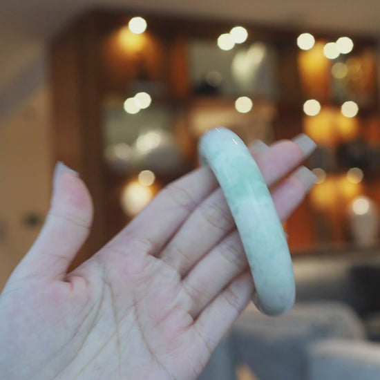Serpentine jade bracelet in a calming tea green shade with natural white veining, hand-carved in a classic round shape for serene elegance – Miruzi