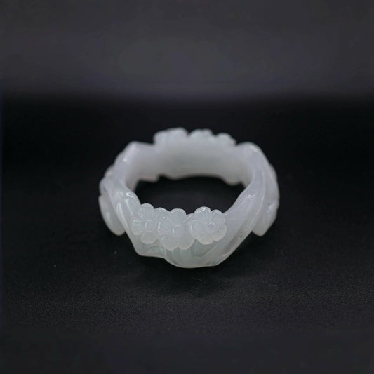 White jade bangle with hand-carved plum blossom branches on both sides, symbolizing quiet resilience and grace

