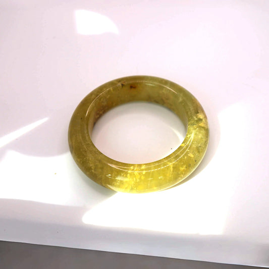 Nature-inspired golden jade jewelry piece with soft light and movement in organic mineral patterns

